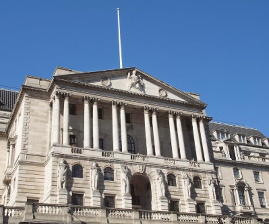 Front view of the historic Bank of England building under a clear blue sky, showcasing its neoclassical architecture and iconic columns.