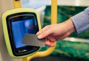 A person uses contactless payment with credit cards on public transport in the UK, highlighting modern commuting benefits.